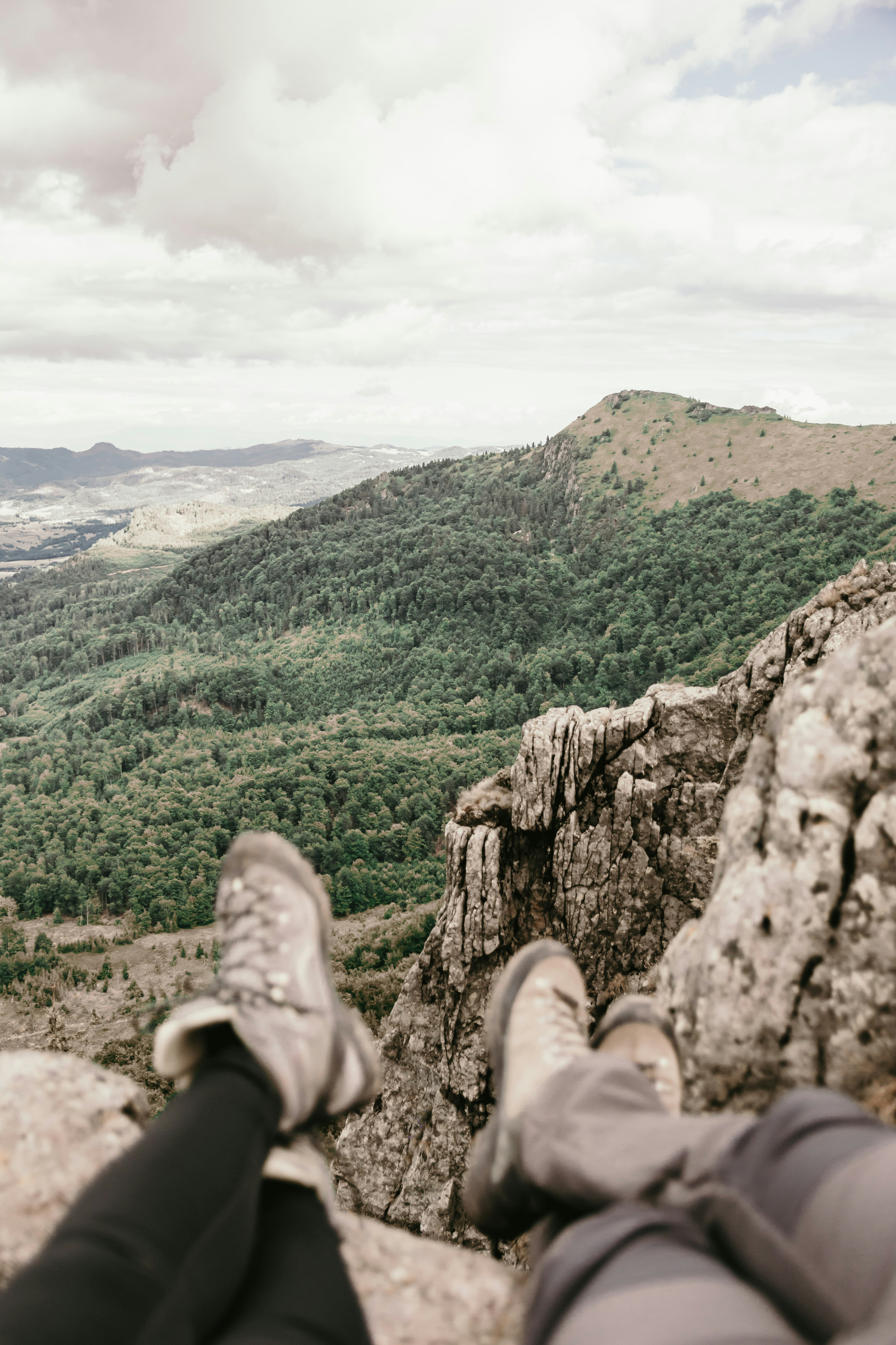 person in gray hiking shoes on brown rock mountain during daytime